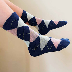 A child sticking out his legs wearing blush pink and navy blue argyle socks