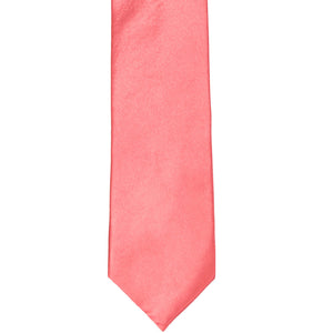 The front of a coral slim tie, laid out flat