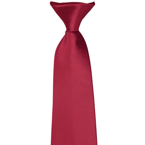 The front of a knot on a pre-tied crimson red clip-on tie