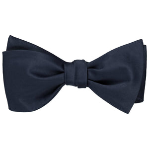 A solid color dark navy blue self-tie bow tie, tied