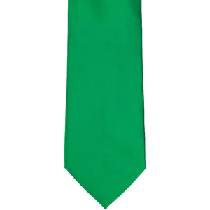 The bottom tip of a kelly green solid tie, laying flat