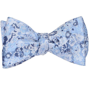 A self-tie bow tie, tied, in a dusty blue floral pattern
