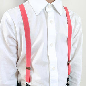 A boy wearing coral suspenders with a white dress shirt
