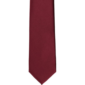 The front of a burgundy slim solid tie, laid out flat