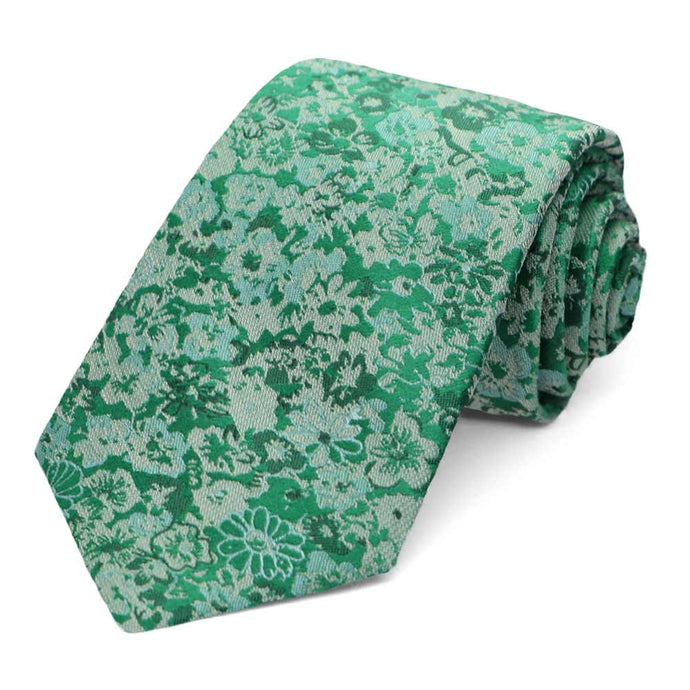 A green floral tie, rolled to show the pattern