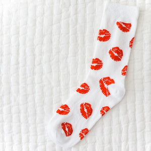 A single white sock covered in a red lipstick kiss pattern