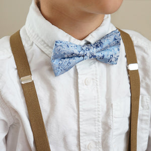 Boy wearing a steel blue floral bow tie and tan suspenders