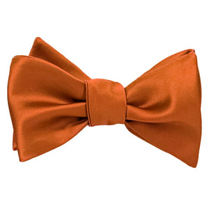 A tied burnt orange self-tie bow tie in a solid color