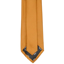 Load image into Gallery viewer, An antique gold necktie with a subtle herringbone texture, featuring a black patterned tip with small white circular details.
