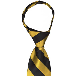 The knot on a black and gold striped zipper tie