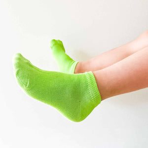 A boy wearing a pair of lime green ankle socks