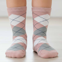 Load image into Gallery viewer, Child wearing blush pink, gray, and white argyle patterned socks on a neutral background