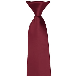 The knot on the front of a burgundy clip-on tie
