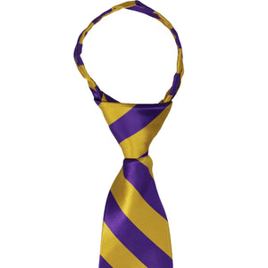 A closeup of the knot on a dark purple and gold striped zipper tie