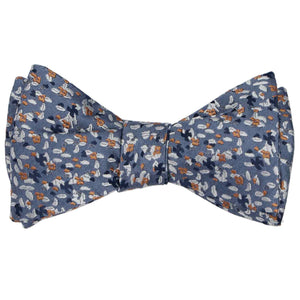 A dusty blue and antique gold grain pattern bow tie, tied