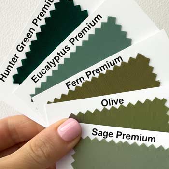 Woman's hand holding an assortment of olive and sage-toned necktie color swatches