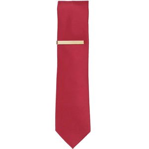 A solid gold tie bar on a red slim tie
