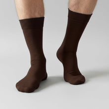 Load image into Gallery viewer, Man wearing brown dress socks on a light gray background