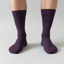 Load image into Gallery viewer, Eggpplant purple socks worn by a man on a light gray background