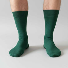 Load image into Gallery viewer, Man modeling hunter green dress socks on light gray background