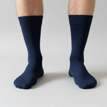 Load image into Gallery viewer, Man wearing navy blue socks on a gray background