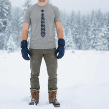 Load image into Gallery viewer, Man wearing a gray t-shirt with a snowflake tie design, green pants, and brown boots standing in a snowy landscape.