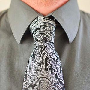Man wearing a black paisley tie with a gray dress shirt