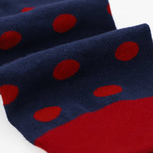 Load image into Gallery viewer, Close-up of a folded knit sock in navy blue with large red polka dots and a solid red cuff, shown on a white background.