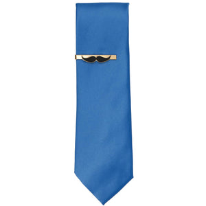 A gold and black mustache tie bar on a blue necktie