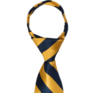 A closeup of the knot on a navy blue and gold bar striped zipper tie
