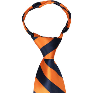 The knot of a navy blue and orange striped zipper tie