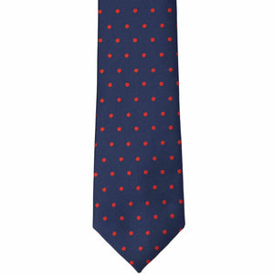 The front of a navy blue and red polka dot tie, laid out flat