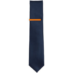 A solid orange tie bar on a navy blue skinny tie