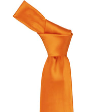Load image into Gallery viewer, Close-up of a solid orange necktie knot, highlighting the bright orange tone and subtle ribbed texture of the fabric.