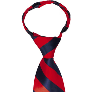 A closeup of the knot on a red and navy blue striped zipper tie