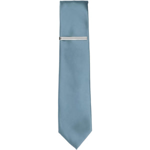A silver tone skinny tie bar on a serene blue slim tie