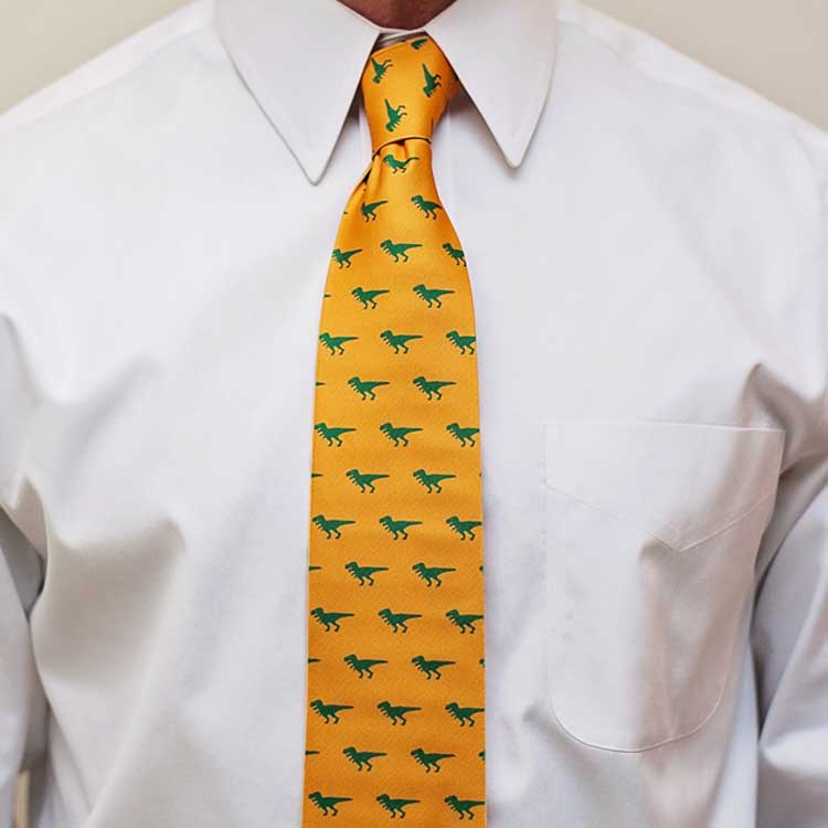 Man wearing a t-rex themed tie in golden yellow and green with a white dress shirt