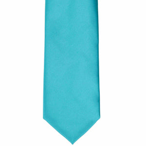 The bottom of a turquoise solid color tie, laid out flat
