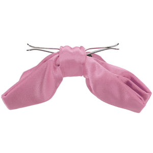 The side view of an antique pink clip-on bow tie, opened