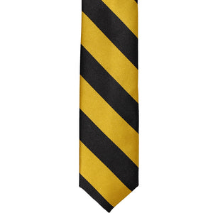 The front of a black and gold striped skinny tie, laid out flat