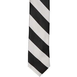 The front of a black and pale silver striped skinny tie, laid out flat