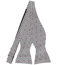 Load image into Gallery viewer, An untied black and white gingham self-tie bow tie, with magenta polka dots across the pattern