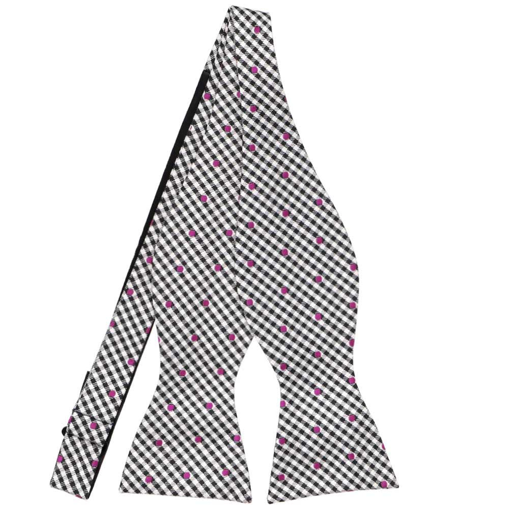 An untied black and white gingham self-tie bow tie, with magenta polka dots across the pattern
