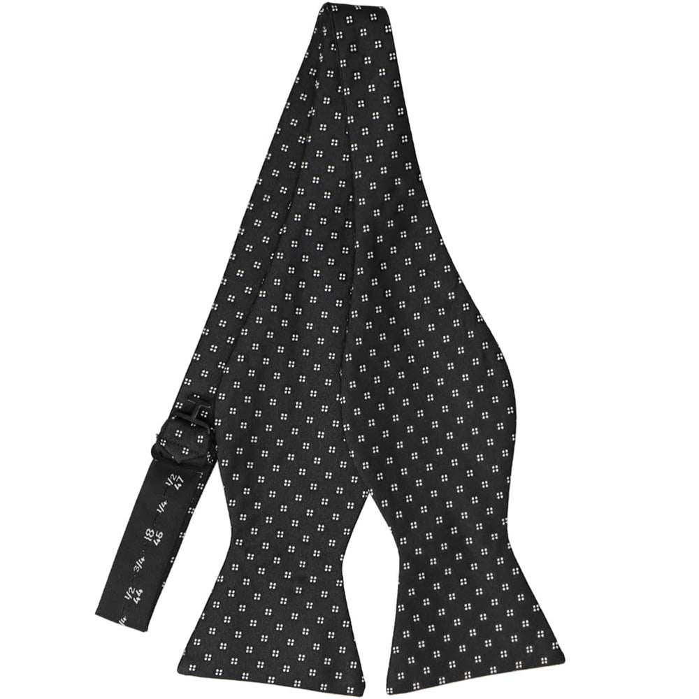 An untied, black self-tie bow tie with tiny white pinpoint dots in groups of four across the pattern