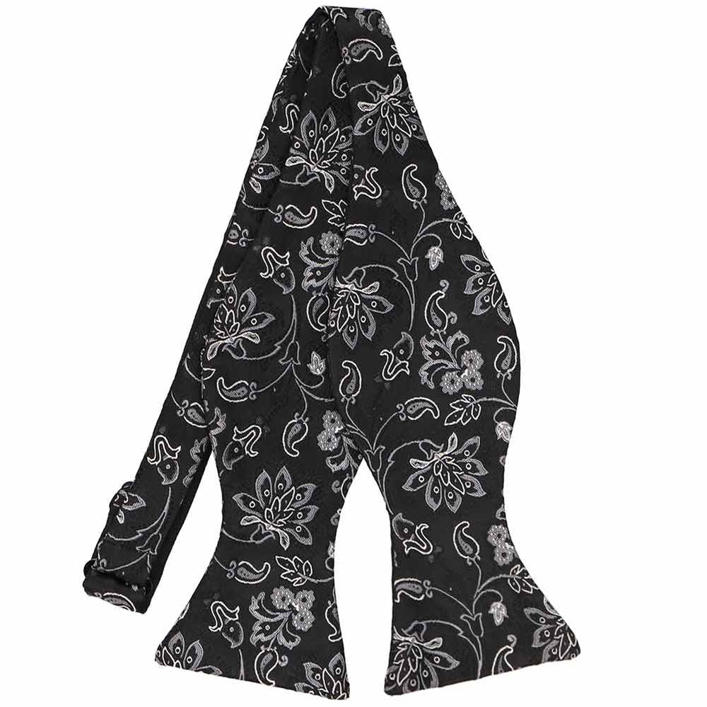 A black and gray floral paisley bow tie, pictured in an untied self-tie style