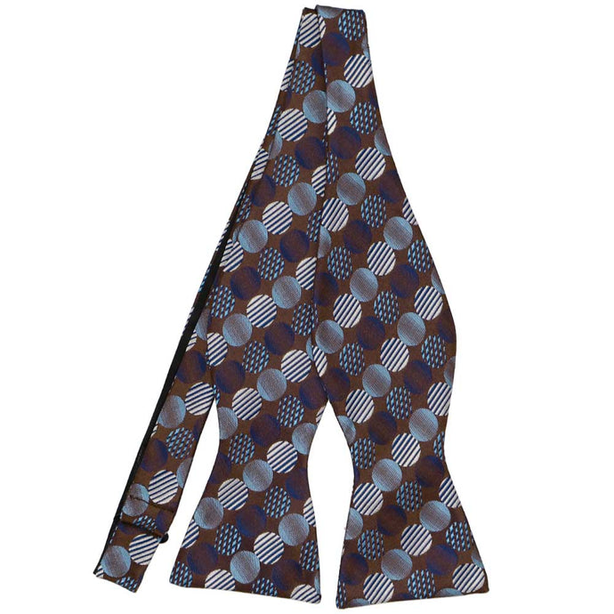 An untied brown self-tie bow tie with large blue dots