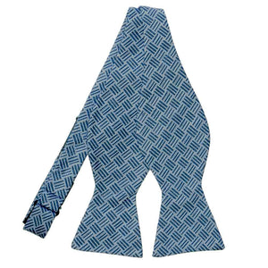 An untied denim blue self-tie bow tie with a darker blue crosshatch pattern overlay