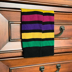 A pair of striped socks in multiple colors hanging out of a sock drawer