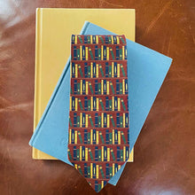Load image into Gallery viewer, A bookshelf themed tie displayed with books on a leather background