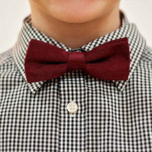 Load image into Gallery viewer, A boy wearing a dark burgundy bow tie with a black and white gingham dress shirt